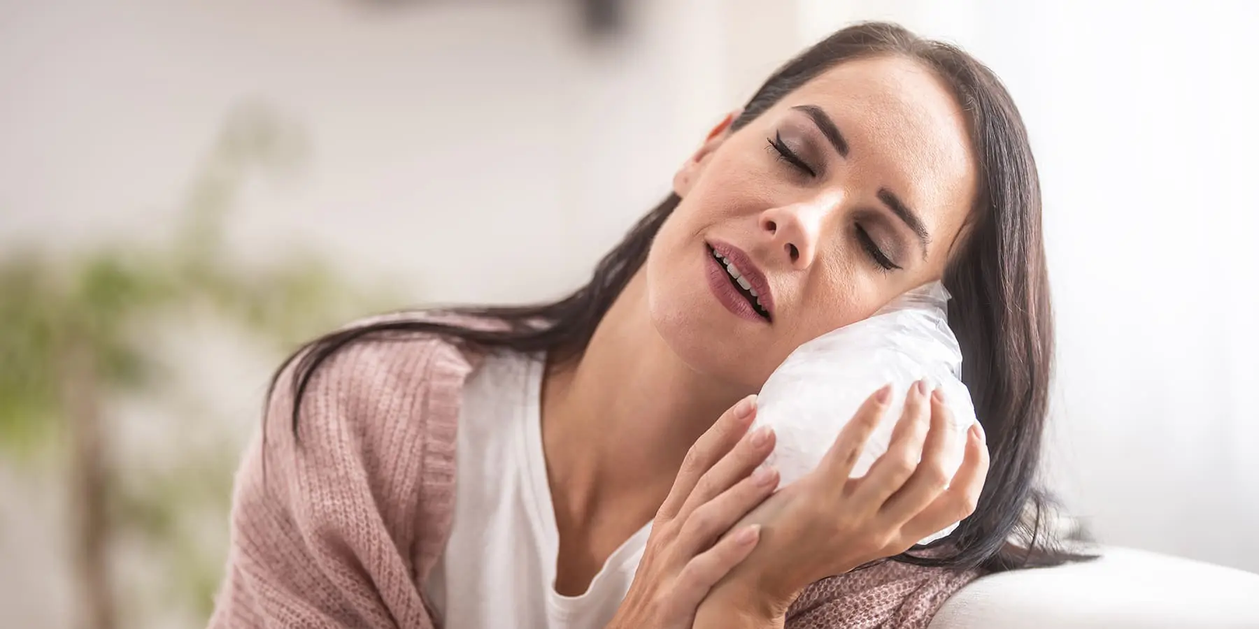 A woman holding an ice pack to her cheek